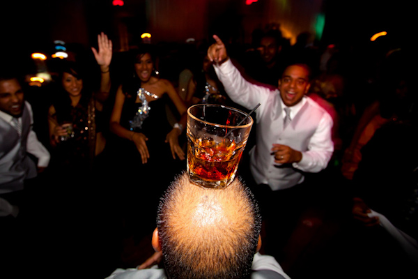 hilarious photo of man balancing a drink on his head during wedding reception - photo by Florida based destination wedding photographer Chip Litherland of Eleven Weddings
